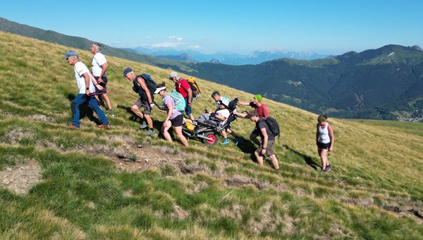 Alpen_der Berg ruft_Monte Bar Eine Gruppe wandert über eine Wiese hoch auf einen Hügel.