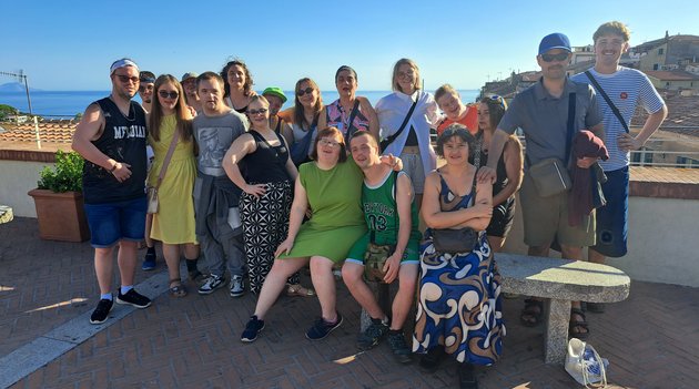 Un groupe de personnes pose sur un toit avec la mer en arrière-plan.