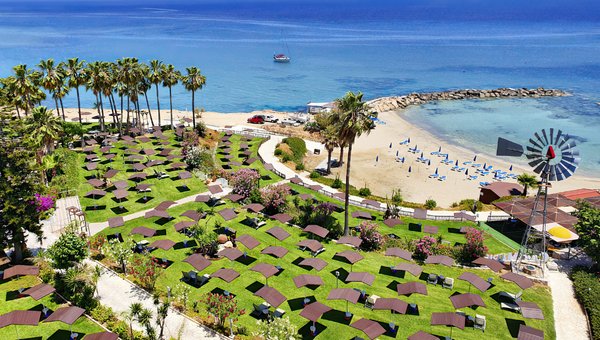 La zone de chaises longues de l'hôtel, entourée de fleurs colorées et de palmiers, directement au bord de la mer.