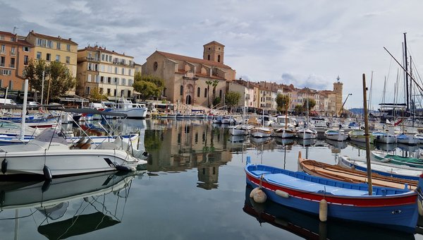 Vue sur un port avec de nombreux bateaux. À l'arrière-plan, on aperçoit la ville avec ses bâtiments anciens.