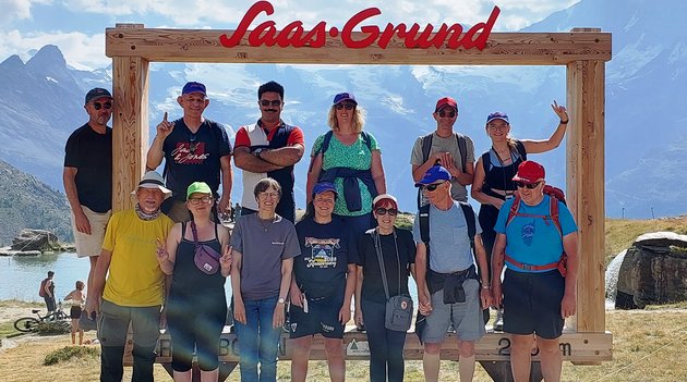 n groupe de personnes pose dans un grand cadre photo avec les montagnes suisses en arrière-plan.