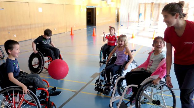 Un groupe d'enfants en fauteuil roulant jouant dans un gymnase.