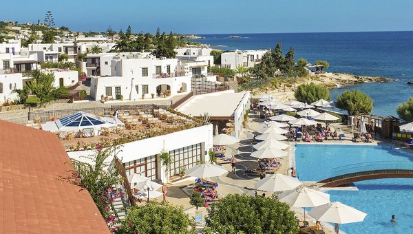 Der Hotelpool mit Liegestühlen und weißen Häusern rundherum.