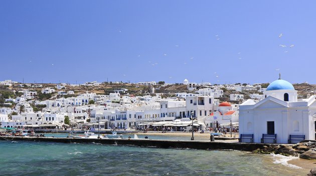 Au premier plan, la mer déchaînée, et à l’arrière-plan, les maisons grecques typiques de l’île de Mykonos.
