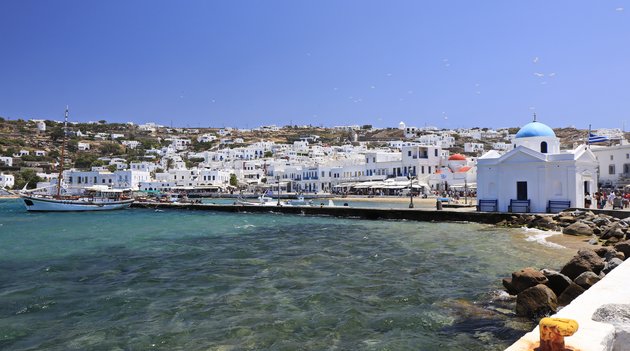 Au premier plan, la mer déchaînée, et à l’arrière-plan, les maisons grecques typiques de l’île de Mykonos.