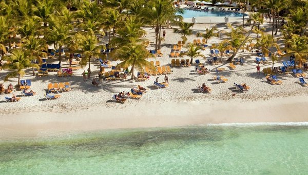 Sicht auf den wunderbarenSandstrand mit vielen Palmen, Pool und Hotel im Hintergrund