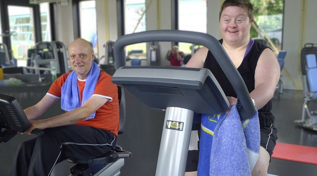 Un homme et une femme riant sur des machines de fitness