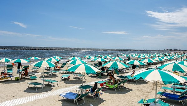 Vue sur la plage de sable privée du Lido degli scacchi avec les parasols blanc-turquoise.