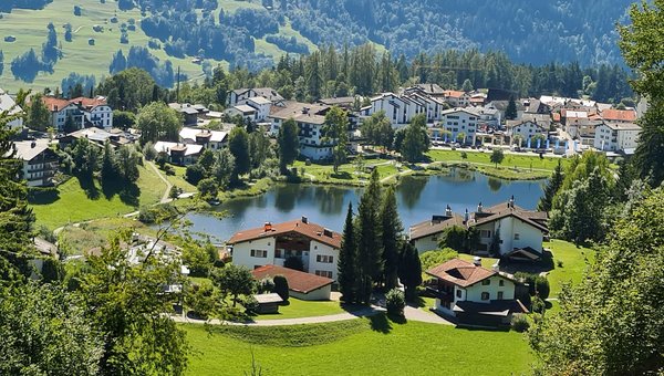 Das Dorf Laax, umgeben von Wäldern, mit einem kleinen See in der Mitte.
